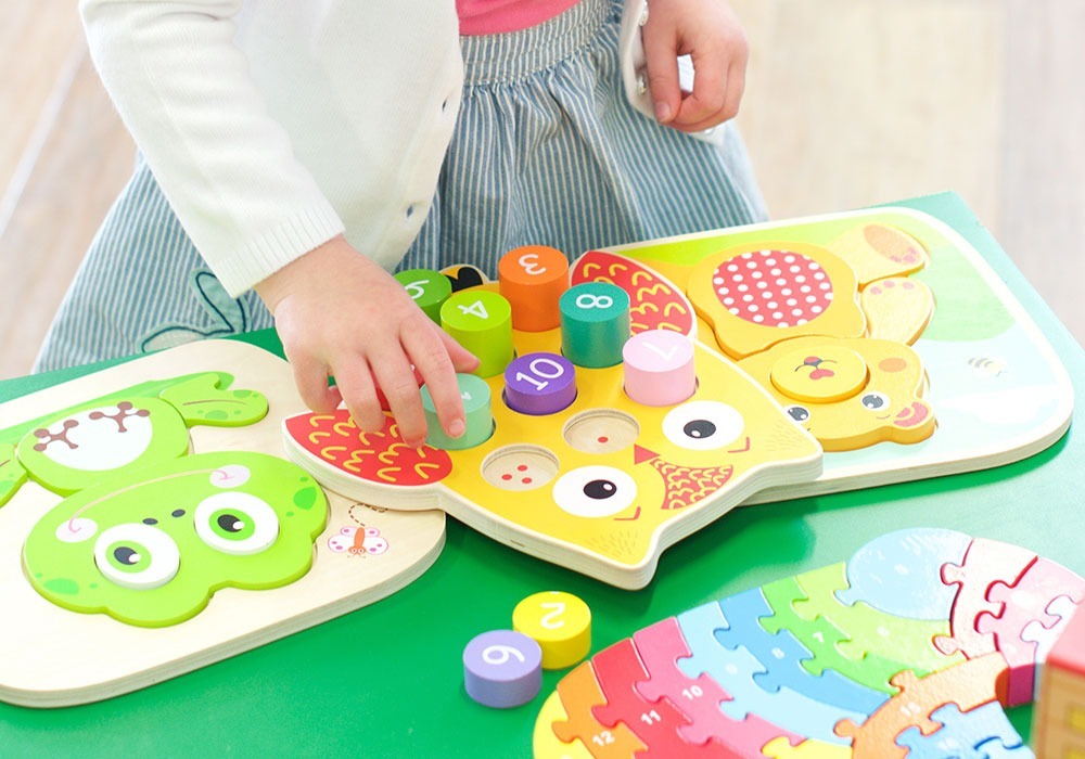 Little girl playing with number puzzle. Toys and puzzles for young children