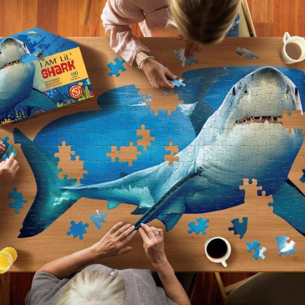 A family doing our Madd Capp Great White Shark jigsaw puzzle and having fun at the table together.