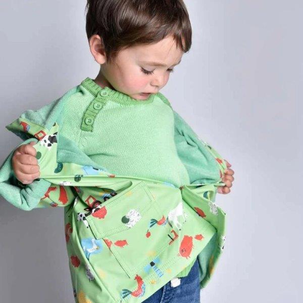 Little boy wearing Powell Craft's Farmyard Raincoat. Buy online with Ebb & Flow Kids.